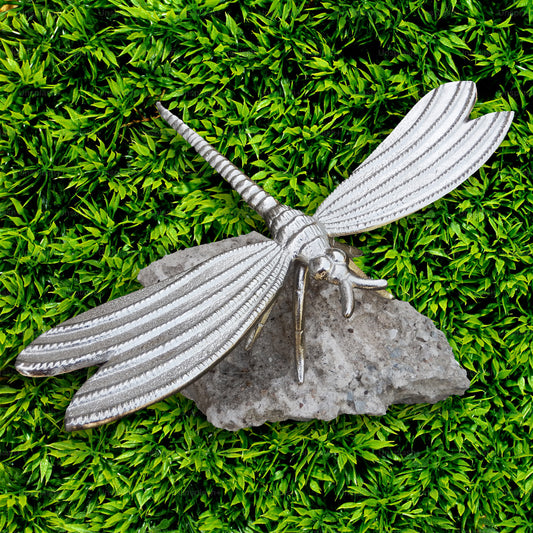 Metallic dragonfly sculpture on a grassy background